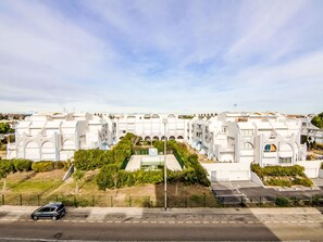 Ett modernt hotellkomplex med flera vita byggnader, en central innergård och en parkeringsplats.
