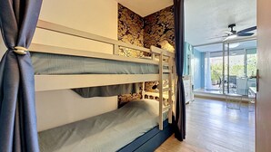 Ein Etagenbett vor einer Steinwand, ein Deckenventilator und Blick auf eine Außenpatio.