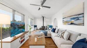 Ein modernes Wohnzimmer mit Kamin, Sofa, Fernseher und Deckenventilator.
