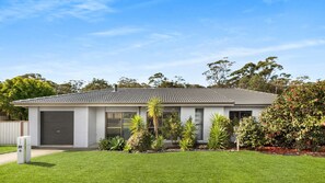 A single-story house with a tiled roof, a garage, and a well-maintained lawn. - Southcoast Haven is the perfect spot for your next getaway (Shoalhaven Heads)