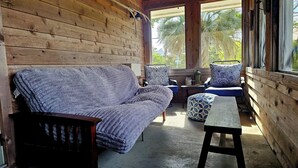 Ein Holzblockhaus-Interieur mit einer Couch, zwei Sesseln, einem kleinen Tisch und einer Bank.