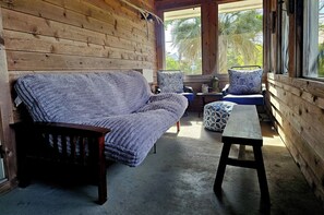 Ein Holzblockhaus-Interieur mit einer Couch, zwei Sesseln, einem kleinen Tisch und einer Bank.
