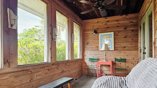 Eine Holzhütte mit einer Bank, einem Tisch, einem Sofa und einem Deckenventilator.