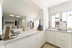 Eine moderne Küche mit weißen Schränken, einer Arbeitsplatte und einem Fenster.