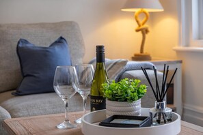 A wooden table with a wine bottle, two glasses, a small plant, a candle holder, and a framed picture. - Crews Nest  Spacious 4 Bedroom Home Near Marinas (Cowes)