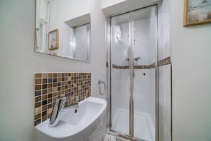 A bathroom with a white sink, a glass shower enclosure, and a tiled backsplash. - Crews Nest  Spacious 4 Bedroom Home Near Marinas (Cowes)