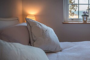 A bed with white bedding, a bedside lamp, and a window with a view of the sea. - The Retreat Stylish 4 bed  sea views   parking (Cowes)