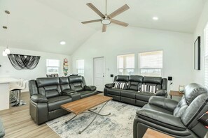 Ein geräumiges Wohnzimmer mit zwei Ledersofas, einem Holztisch und einem Deckenventilator.