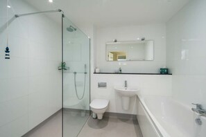 A modern bathroom with a glass-enclosed shower, a white toilet, a sink, and a bathtub. - Mainsail  Coastal Living on Prestigious Road (Cowes)