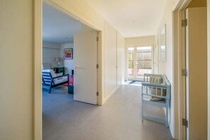 A hallway with a bed, a chair, and a door leading to another room. - Mainsail  Coastal Living on Prestigious Road (Cowes)