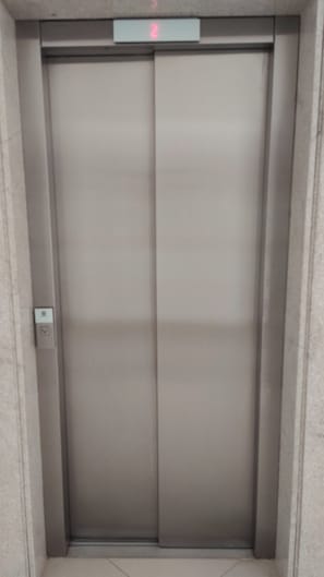 A closed elevator door with a digital display above it.