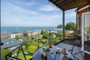 A balcony with a table set for tea, overlooking a residential area and the sea. - Seaview Apartment  2   Bed Solent Views   Parking (Cowes)
