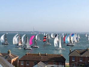 A marina with multiple sailboats, buildings in the foreground, and a distant lighthouse. - Seaview Apartment  2   Bed Solent Views   Parking (Cowes)