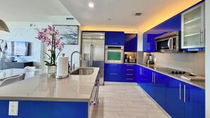 Una cocina moderna con armarios azules, electrodomésticos de acero inoxidable y una isla central con lavamanos.