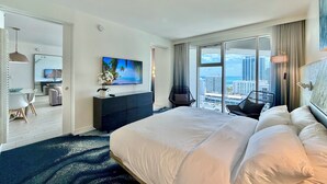 Una habitación de hotel moderna con una cama grande, televisión de pantalla plana, vistas a la ciudad y un balcón.