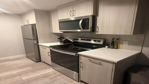 Uma cozinha moderna com eletrodomésticos de aço inoxidável, armários de madeira e painel de azulejos.