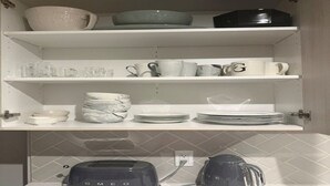 Cozinha com prateleiras brancas que exibem diversos utensílios e uma torradeira.