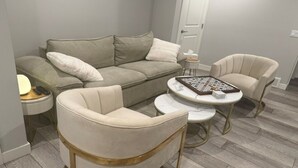 Uma sala de estar com um sofá, duas poltronas, uma mesa de centro e uma mesinha lateral.