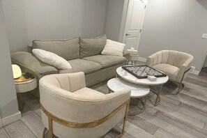Ein Wohnzimmer mit einer Couch, zwei Sesseln, einem Couchtisch und einem kleinen Beistelltisch.