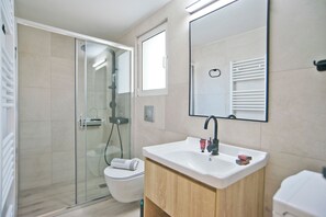 Une salle de bain moderne avec une douche à parois de verre, un lavabo blanc et un grand miroir.