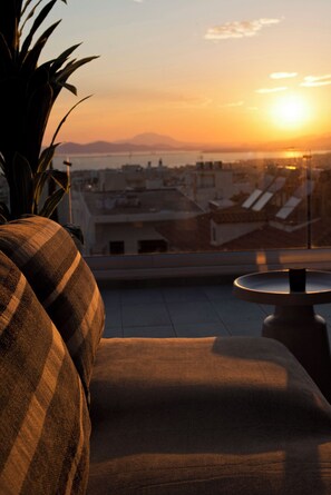 Une vue sur le coucher de soleil depuis un balcon, avec un canapé et une table.