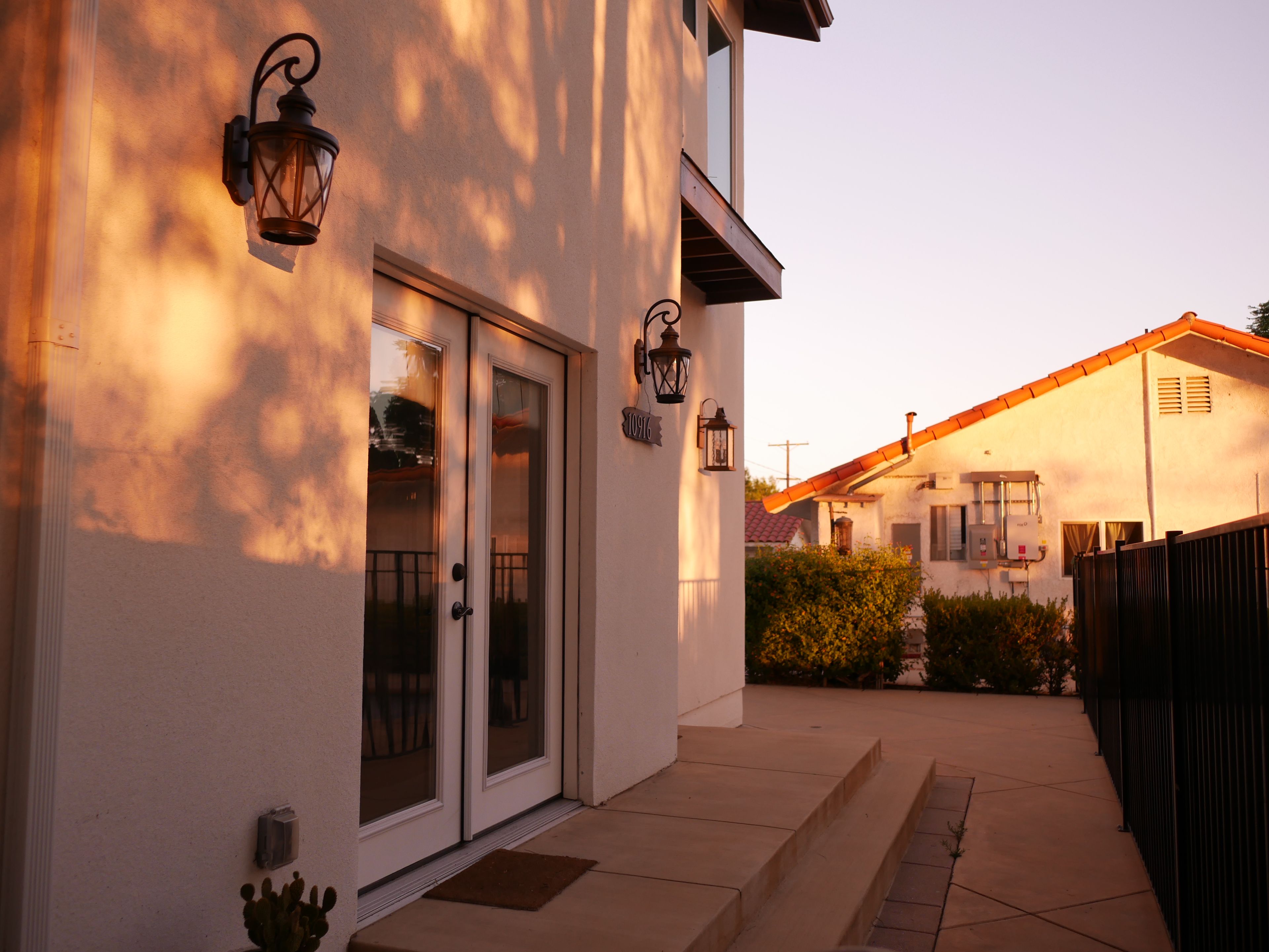 A residential building with a glass door entrance, a small porch, and a visible number '10916' on the wall.