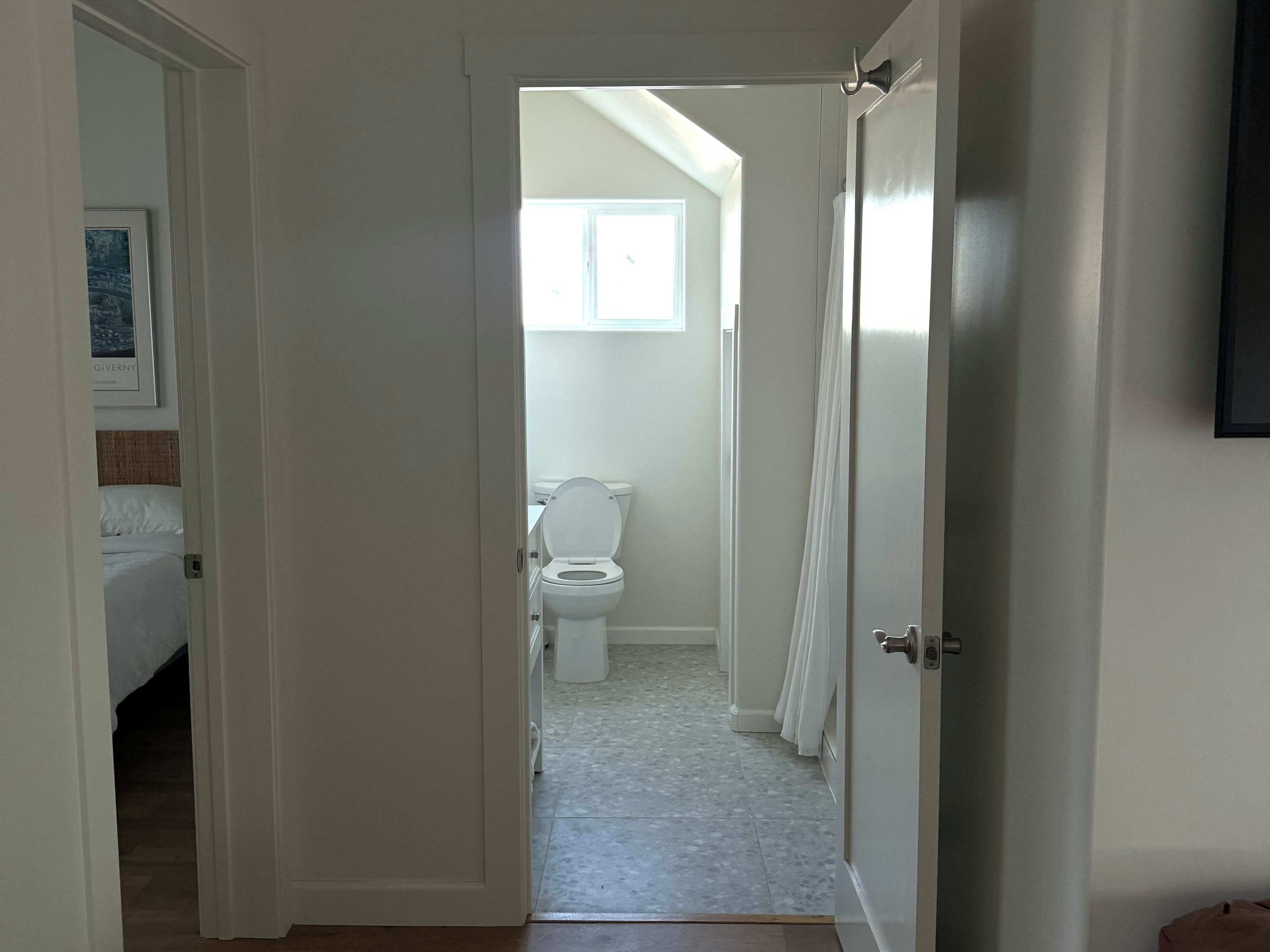 A hotel room with a bed, a bathroom with a toilet, and a window.