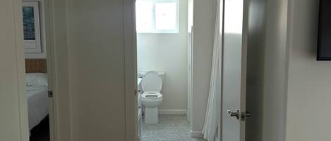 A hotel room with a bed, a bathroom with a toilet, and a window.