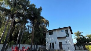 Ein modernes, zweistöckiges Haus mit Swimmingpool, umgeben von Bäumen und einem weißen Zaun.