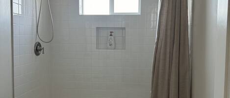 Ein Badezimmer mit Dusche, Toilette und Fenster.