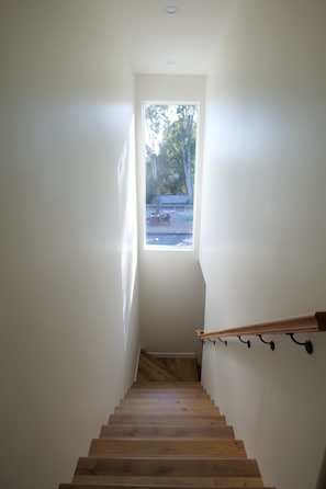 Eine Holzt Treppe mit Blick ins Freie durch ein Fenster.