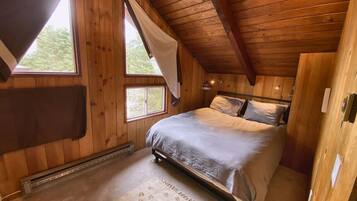 Camera da letto con pannelli in legno, un letto, una finestra con tenda e un termosifone.
