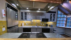 A kitchen with a stainless steel refrigerator, a sink, a microwave, and a window with a view. - Iconic A-Frame | Steps to Alyeska + Restaurants (Anchorage)