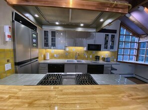 A kitchen with a stainless steel refrigerator, a sink, a microwave, and a window with a view.