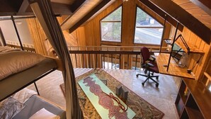 A loft-style room with a desk, chair, and bunk beds. - Iconic A-Frame | Steps to Alyeska + Restaurants (Anchorage)