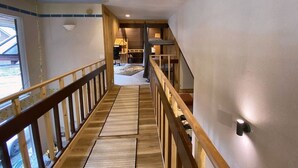 A staircase with wooden railings leading to a bedroom with a bed and a nightstand. - Iconic A-Frame | Steps to Alyeska + Restaurants (Anchorage)