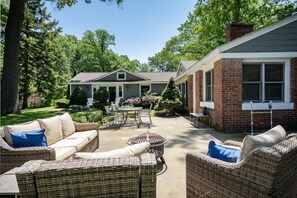 A patio area with wicker furniture, a table, and chairs. - Lakeside Retreat Mona Lake Waterfront Sleeps 12 (Norton Shores)