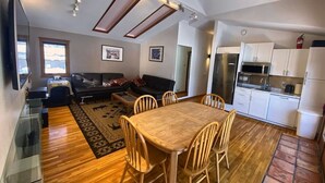 A modern living space with a dining area, kitchen, and seating area.