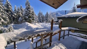 A wooden fence with snow accumulation, a wire fence, and a building with a green roof in a snowy landscape.