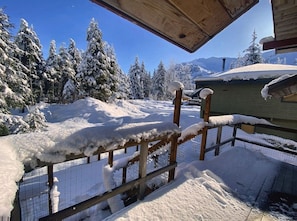 Ett trästaket med snö på, ett stängsel av ståltråd och en byggnad med ett grönt tak i ett snötäckt landskap.