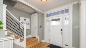Una escalera que lleva a una plataforma con una puerta, una lámpara arriba y una planta a la izquierda.