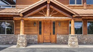 Une cabane en rondins avec des fondations en pierre, une porte d’entrée en bois et un pilier en pierre de chaque côté.