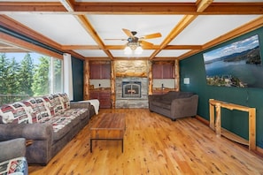 Una sala de estar acogedora con chimenea, piso de madera y vista a un lago.