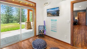 Une pièce dotée d’une grande porte-fenêtre coulissante, d’une cheminée en pierre, d’un porte-tapis de yoga et d’un calendrier mural.