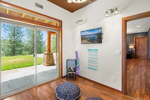 Una habitación con un amplio ventanal corredero, una chimenea de piedra, un soporte para colchonetas de yoga y un calendario en la pared.