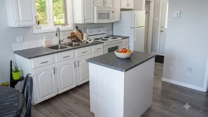 Una cucina moderna con mobili bianchi, un'isola centrale e un forno a microonde sopra i fornelli.