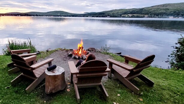 Area relax sul lago con un braciere, panche e tavolo da picnic.
