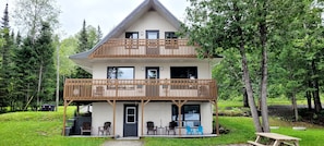 A two-story house with a balcony, a door, and outdoor seating.