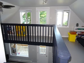 Ein Zimmer mit schwarzem Geländer, weißen Wänden und einem gelben Tisch mit Gesellschaftsspielen.