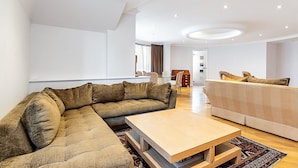 Ein modernes Wohnzimmer mit einem Ecksofa, einem zusätzlichen Sofa, einem Couchtisch und einem Essbereich mit Tisch und Stühlen.